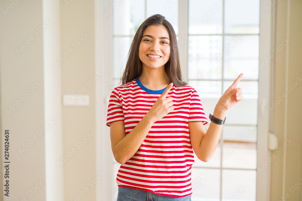 Young beautiful woman wearing casual t-shirt smiling and looking at the camera pointing with two hands and fingers to the side. Young beautiful woman wearing casual t-shirt smiling and looking at the camera pointing with two hands and fingers to the side.