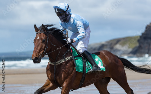 Close up on galloping race horse and jockey on the beach