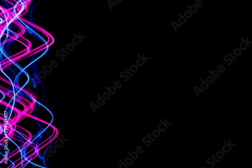 Long exposure, light painting photography. Vibrant electric blue streaks and ripples of neon pink, against a black background