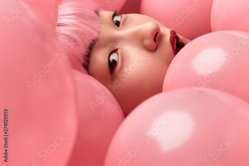 Face of amazed Asian woman in pink balloons