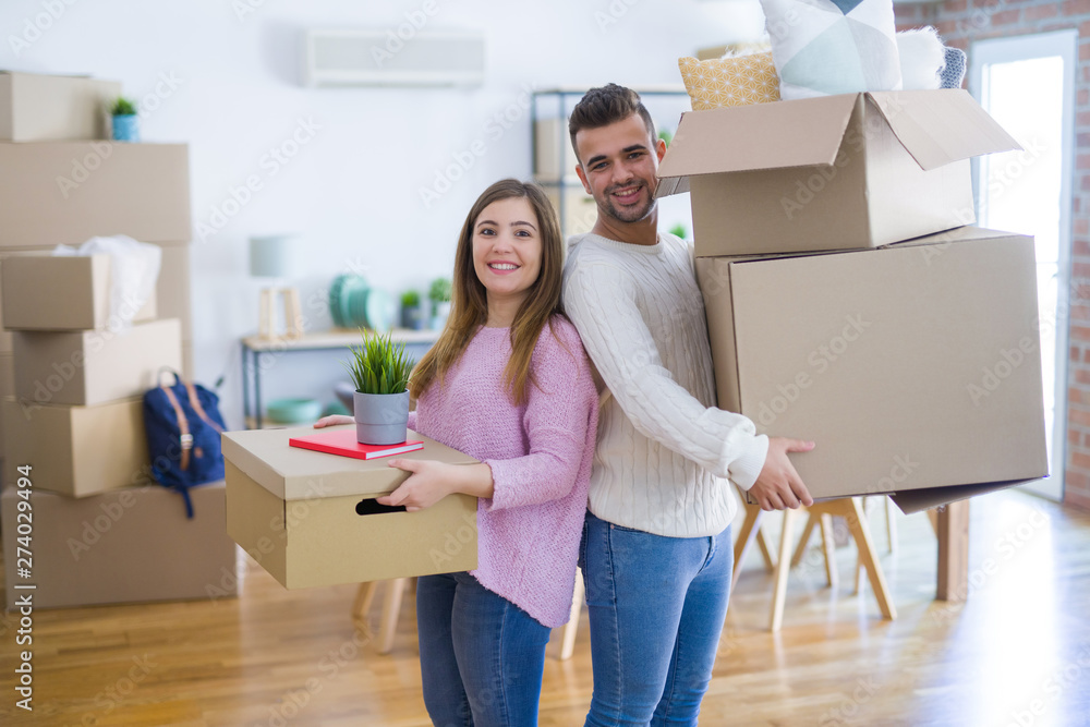 Young beautiful couple in love moving to new home, holding cardboard boxes very happy and cheerful for new apartment Young beautiful couple in love moving to new home, holding cardboard boxes very happy and cheerful for new apartment