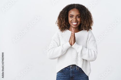 Please do me favor. Charming pleasant friendly-looking african american smiling woman press palms together supplication, pray gesture asking help, grinning thankful lend money white background photo
