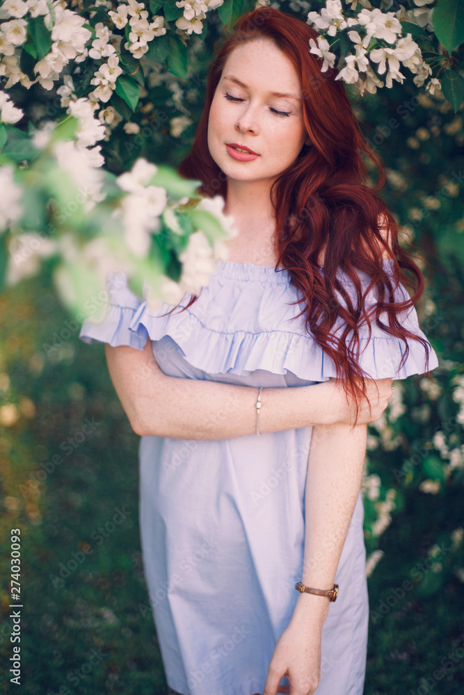 Model with red hair posing in a blooming apple tree. Model with red hair posing in a blooming apple tree.