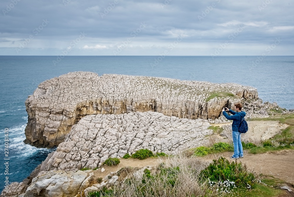 A woman takes photos with her smartphone on the coast