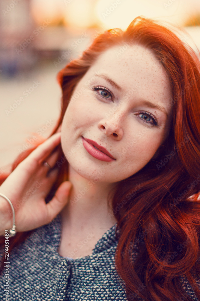 Red-haired Model in a coat posing against the backdrop of the sunset on the street. Red-haired Model in a coat posing against the backdrop of the sunset on the street.