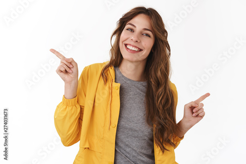 Which way. Amused happy cheerful good-looking european girl curly chestnut hair tilting head joyful asking opinion what choice make pointing left right sideways picking between variants photo