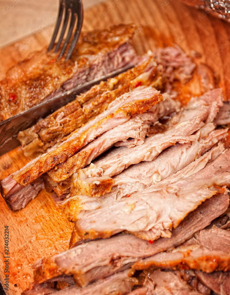 A juicy fresh baked pork with herbs and spice on wooden cutting board.
