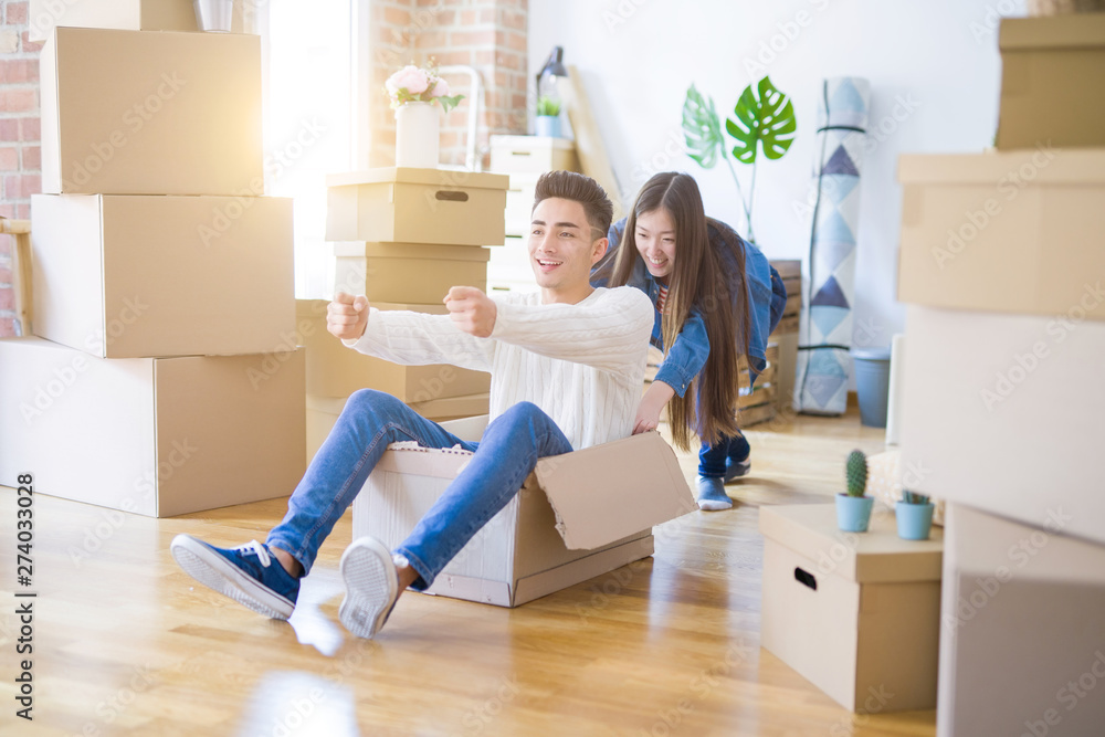 Funny asian couple having fun, riding inside cardboard box smiling happy, very excited moving to a new house Funny asian couple having fun, riding inside cardboard box smiling happy, very excited moving to a new house