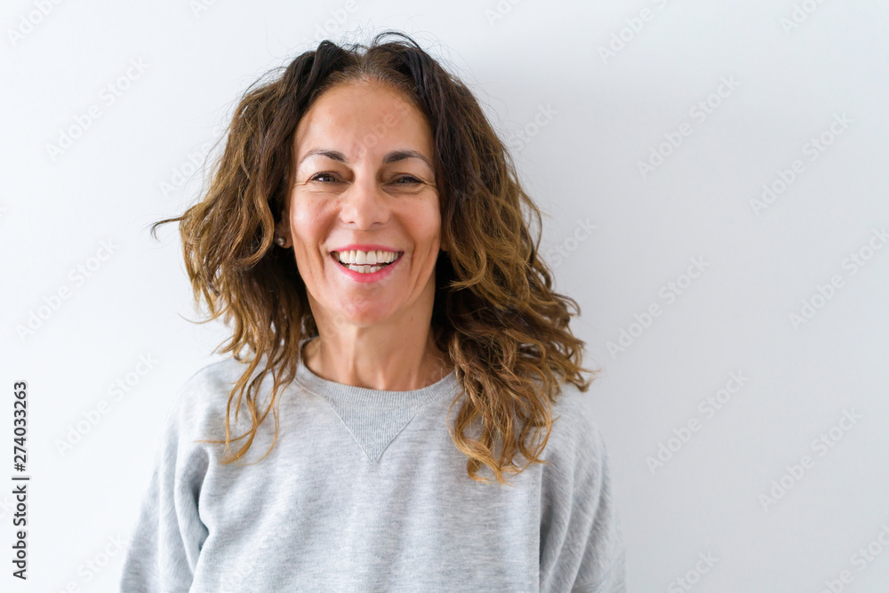 Beautiful middle age woman with curly hair smiling cheerful and happy, laughing with a big smile on face showing teeth over white isolated background Beautiful middle age woman with curly hair smiling cheerful and happy, laughing with a big smile on face showing teeth over white isolated background