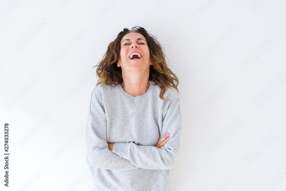 Beautiful middle age woman with curly hair smiling cheerful and happy with arms crossed, laughing with a big smile on face showing teeth over white isolated background Beautiful middle age woman with curly hair smiling cheerful and happy with arms crossed, laughing with a big smile on face showing teeth over white isolated background