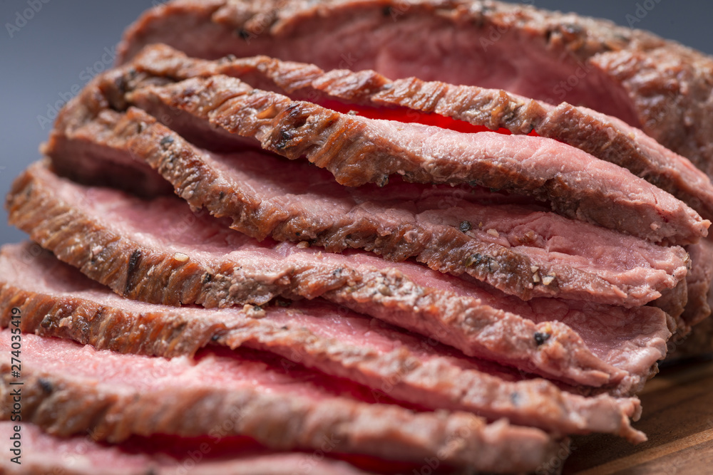 Sliced Grass Fed juicy Corn Roast Beef on natural wood cutting board. Sliced Grass Fed juicy Corn Roast Beef on natural wood cutting board.