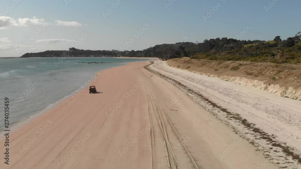 Aerial drone follow tracking shot of a dune buggy speeding on the sandy beach near the water Aerial drone follow tracking shot of a dune buggy speeding on the sandy beach near the water