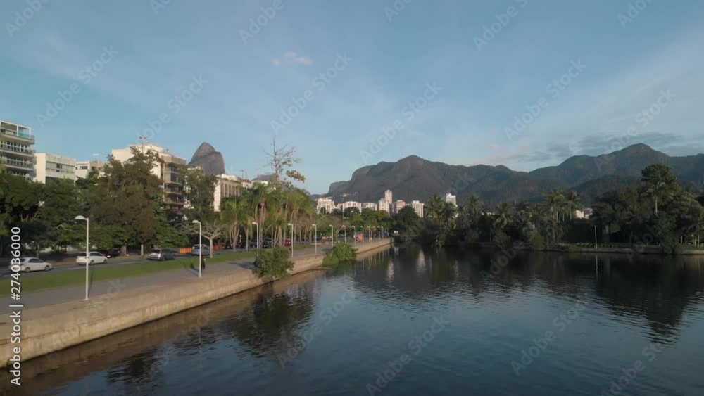 Aerial backward panning alongside the city lake of Rio de Janeiro with people doing their morning exercise running and riding a bicycle Aerial backward panning alongside the city lake of Rio de Janeiro with people doing their morning exercise running and riding a bicycle