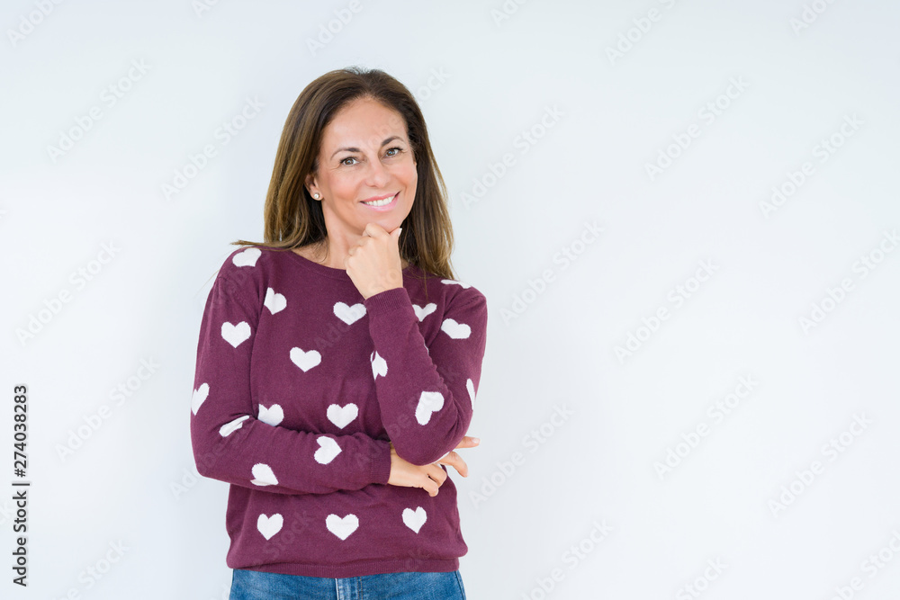 Beautiful middle age woman wearing heart sweater over isolated background looking confident at the camera with smile with crossed arms and hand raised on chin. Thinking positive. Beautiful middle age woman wearing heart sweater over isolated background looking confident at the camera with smile with crossed arms and hand raised on chin. Thinking positive.
