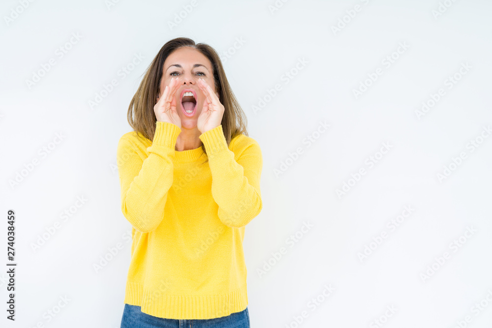 Beautiful middle age woman wearing yellow sweater over isolated background Shouting angry out loud with hands over mouth Beautiful middle age woman wearing yellow sweater over isolated background Shouting angry out loud with hands over mouth