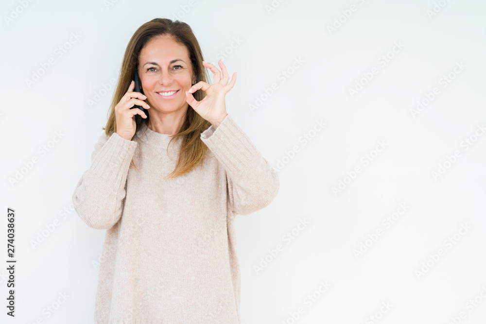 Middle age woman talking on smartphone over isolated background doing ok sign with fingers, excellent symbol Middle age woman talking on smartphone over isolated background doing ok sign with fingers, excellent symbol