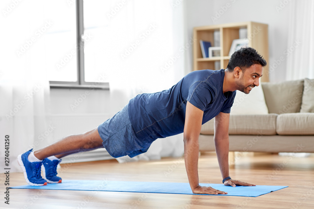 fitness, sport, training and concept - indian man doing push ups at home fitness, sport, training and concept - indian man doing push ups at home