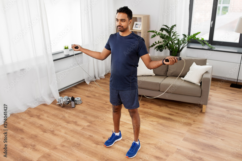 fitness, sport, exercising and healthy lifestyle concept - indian man skipping with jump rope at home fitness, sport, exercising and healthy lifestyle concept - indian man skipping with jump rope at home