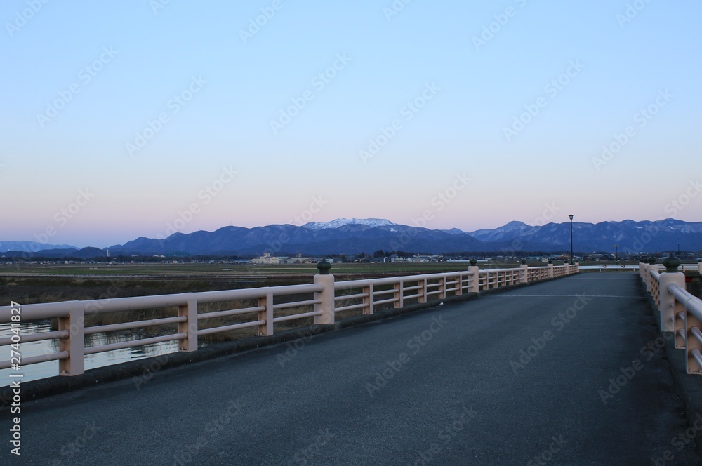 橋から見た夕暮れ時の山々と町の様子です