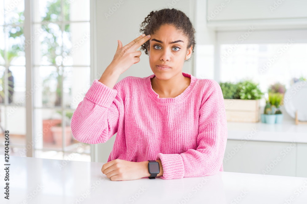 Beautiful african american woman with afro hair wearing casual pink sweater Shooting and killing oneself pointing hand and fingers to head like gun, suicide gesture. Beautiful african american woman with afro hair wearing casual pink sweater Shooting and killing oneself pointing hand and fingers to head like gun, suicide gesture.