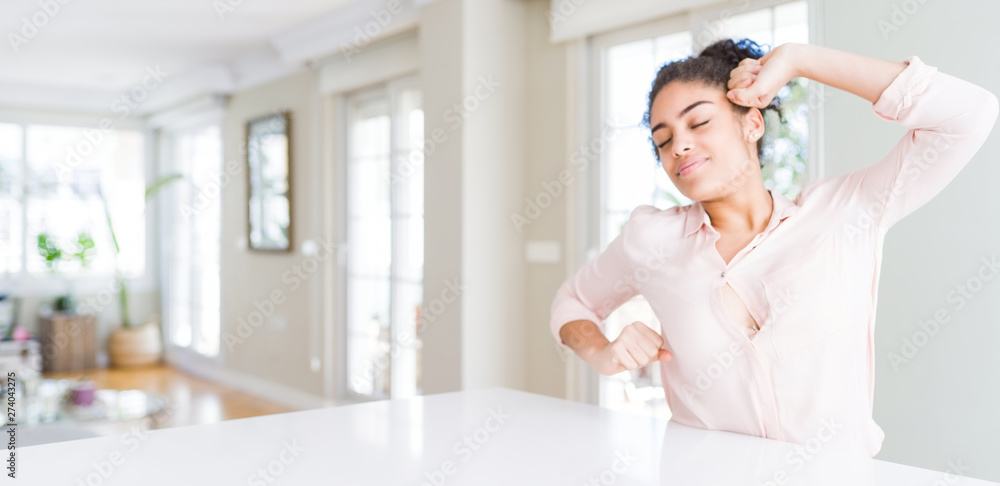 Fototapeta premium Wide angle of beautiful african american woman with afro hair stretching back, tired and relaxed, sleepy and yawning for early morning