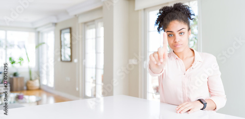 Wide angle of beautiful african american woman with afro hair Pointing with finger up and angry expression  showing no gesture
