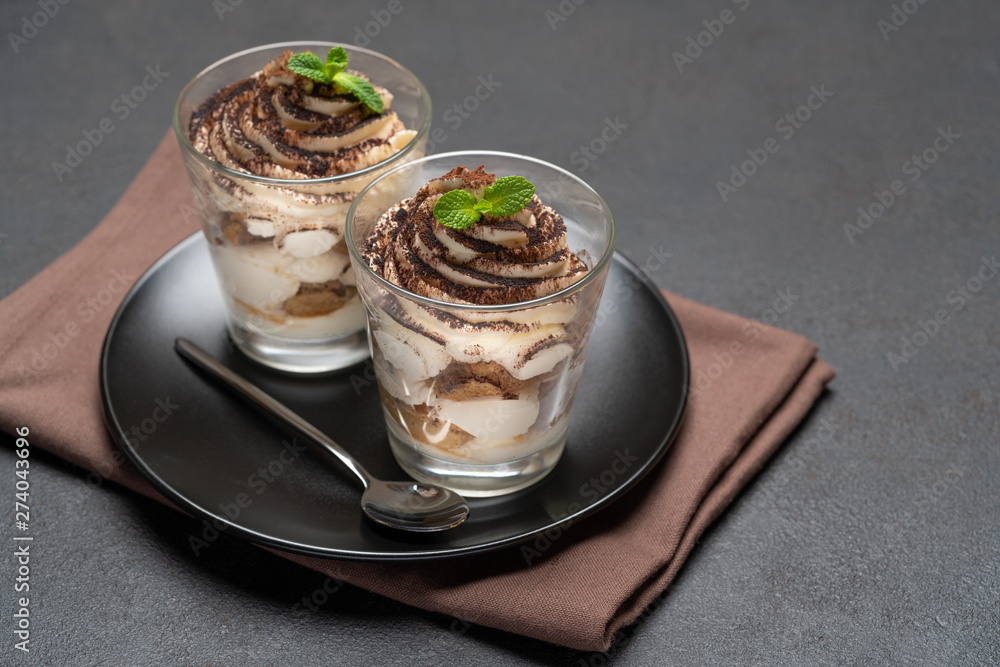 Classic tiramisu dessert in a glass on dark concrete background Classic tiramisu dessert in a glass on dark concrete background