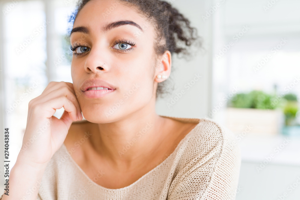 Beautiful young african american woman with blue eyes relaxing at home, with confident expression on face Beautiful young african american woman with blue eyes relaxing at home, with confident expression on face
