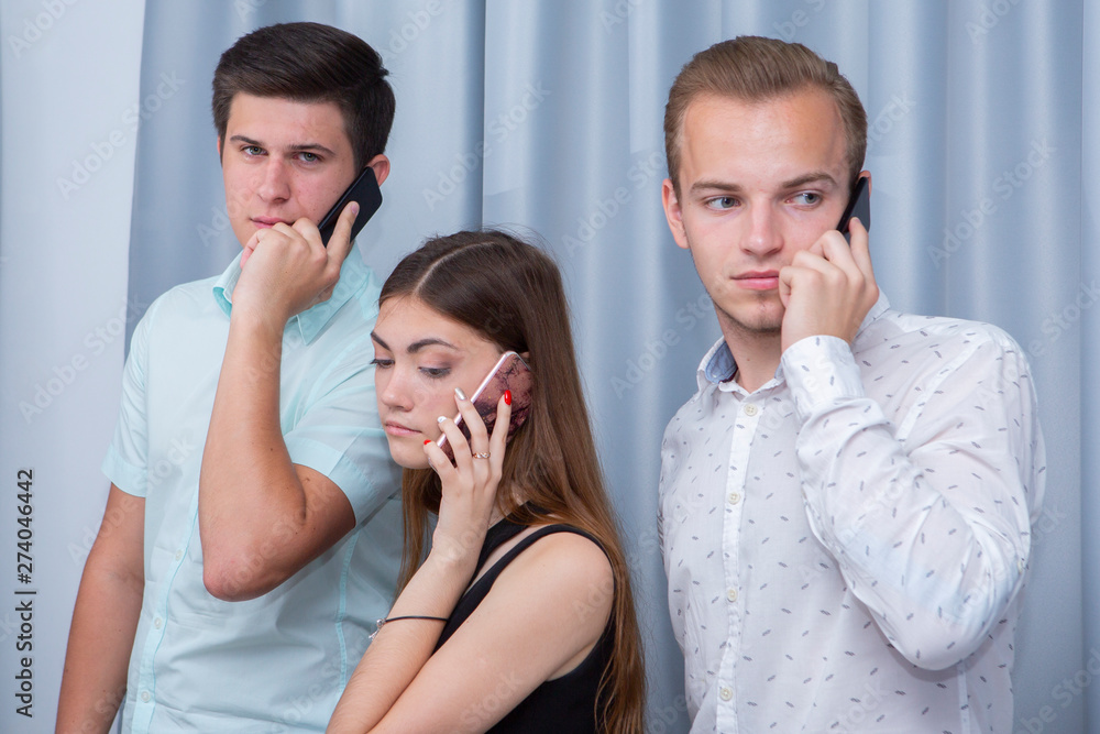 Three young friends standing outdoors and looking at mobile phone. Three young friends standing outdoors and looking at mobile phone.