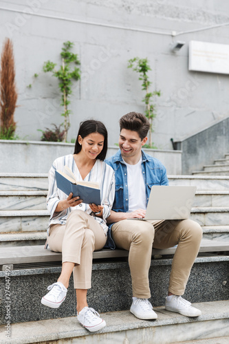 Amazing loving couple business people colleagues outdoors outside on steps using laptop computer reading book.