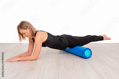 Beautiful woman in sportswear, Pilates instructor stretching and warming up with foam roller. The plank exercise with emphasis on the roll fitness.