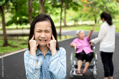 Asian daughter closed ears with hands, little child girl did not want to hear parents,grandmother and mother arguing,quarreling in outdoor park,problems in multi generation family,quarrel concept