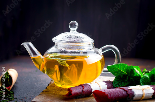 Hot mint tea in a tea pot and  dry fruits leather roll photo