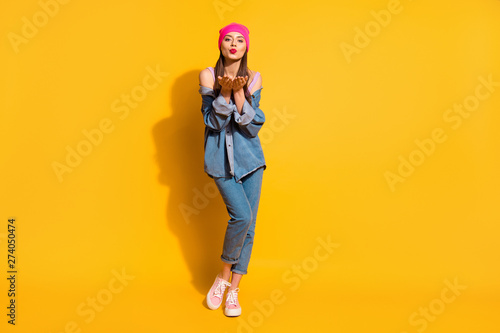 Full length body size photo beautiful funny she her teen lady long hairdo hands arms open palms send air kisses lipstick wear casual jeans denim jacket shoes pink hat isolated yellow bright background