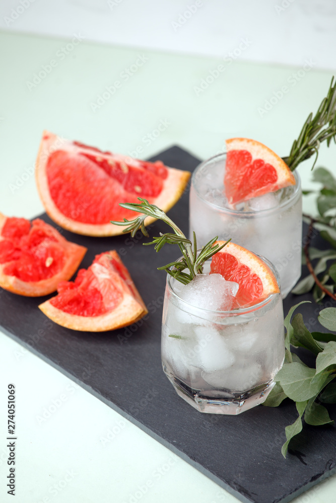Glass of refreshing grapefruit drink with rosemary on table, summer resort menu, bar cart concept, copy space Glass of refreshing grapefruit drink with rosemary on table, summer resort menu, bar cart concept, copy space