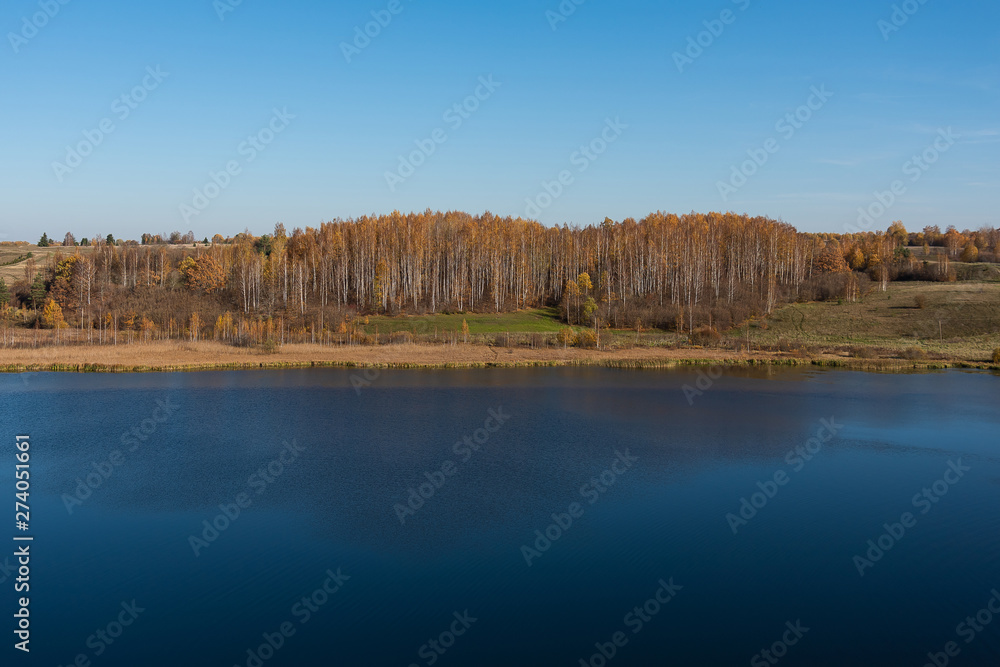 autumn landscape with Golden foliage, blue clear sky and deep lake