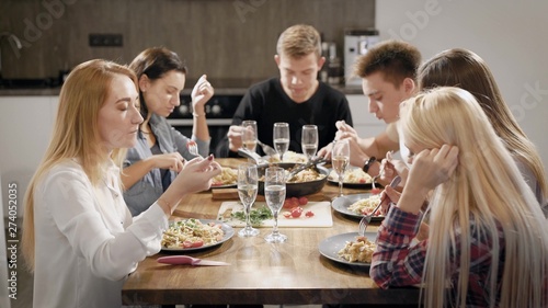 Happy young people dinning at table in kitchen