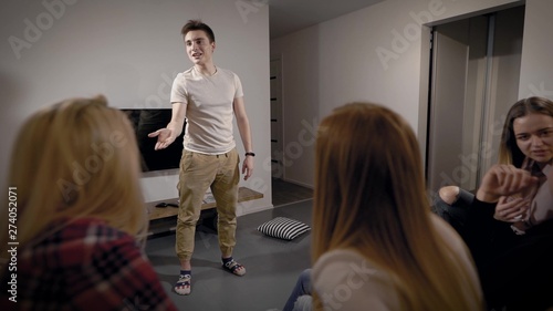 Happy smiling teens playing charades in living room, fun game for a party.