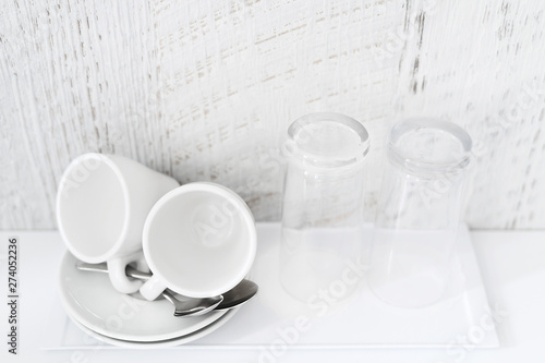 Coffee and tea making set of white cups, saucers, tea spoons and glasses on white porcelain tray. Hotel accomodation. Copy space. © LanaUst