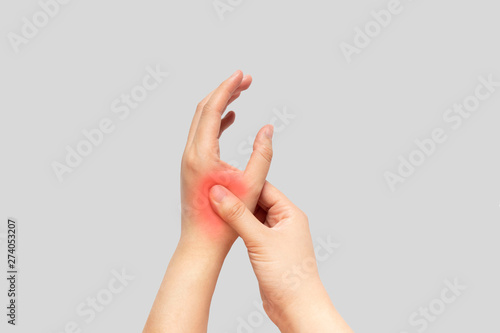 Young female suffering from pain in hands and massaging her painful hands isolated gray background. Causes of hurt include carpal tunnel syndrome, fractures, arthritis, gout attack or trigger finger. photo