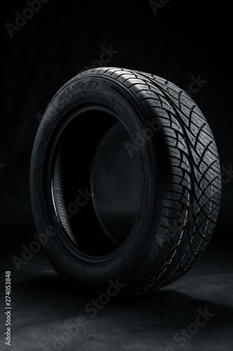 Brand new modern car tyre on a black background. Studio shot