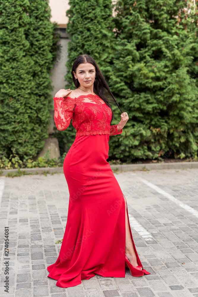 Beautiful brunette in red dress against urban landscape Beautiful brunette in red dress against urban landscape