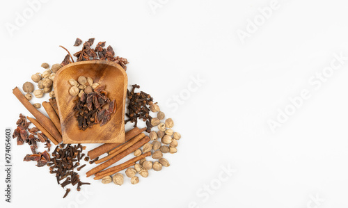 top view isolated dried spices such as cardamom clove cinnamon and nutmeg placed around wooden bowl with put some sweet basil, alternative drugs or nature medicine concept,