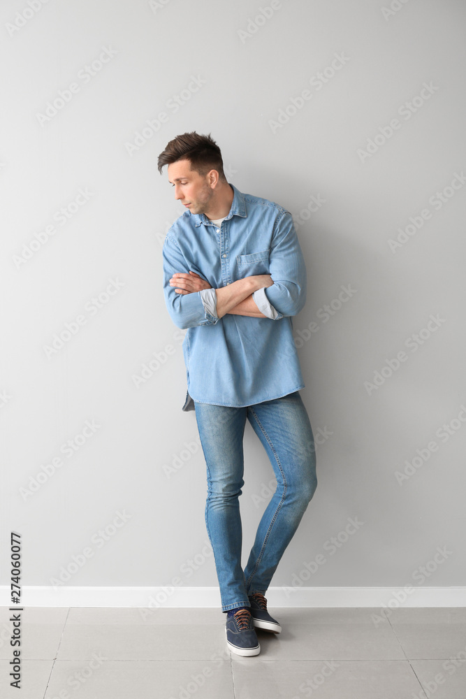 Fototapeta premium Fashionable young man near light wall