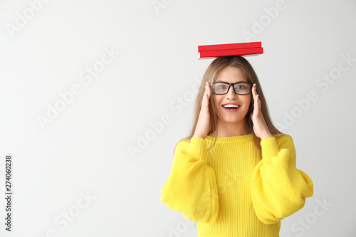 Happy young woman with books on light background