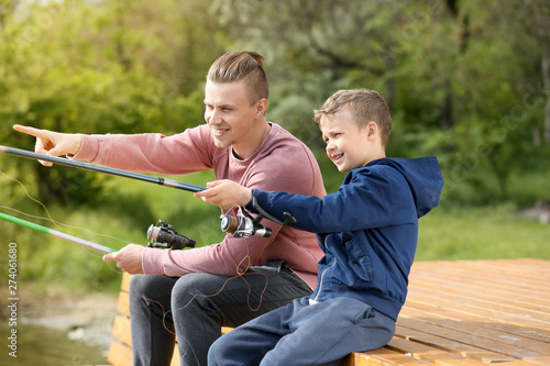 Father and son fishing together on river