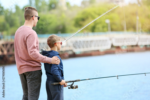 Father and son fishing together on river