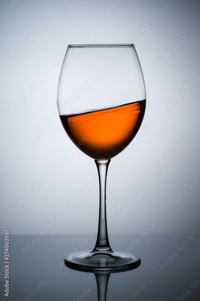 Amber wine. A splash of wine in a glass. Liquid in a glass. Traditional wine according to the ancient Georgian technology. Concept with a glass of wine. Copy space. Close up and vertical orientation. Amber wine. A splash of wine in a glass. Liquid in a glass. Traditional wine according to the ancient Georgian technology. Concept with a glass of wine. Copy space. Close up and vertical orientation.