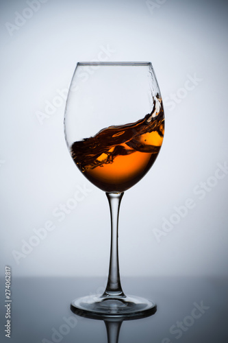 Amber wine. A splash of wine in a glass. Liquid in a glass. Traditional wine according to the ancient Georgian technology. Concept with a glass of wine. Copy space. Close up and vertical orientation.