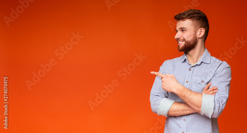 Young redhaired guy showing with finger on copy space
